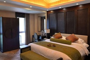 Ein Hotelzimmer mit einem großen Bett, einem Schreibtisch, einem Stuhl und einem Kleiderschrank.