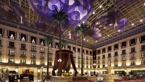 A spacious lobby with a high ceiling, large decorative elements, and a central fountain. - Zhongjia Palace Hot Spring Hotel (Beijing)