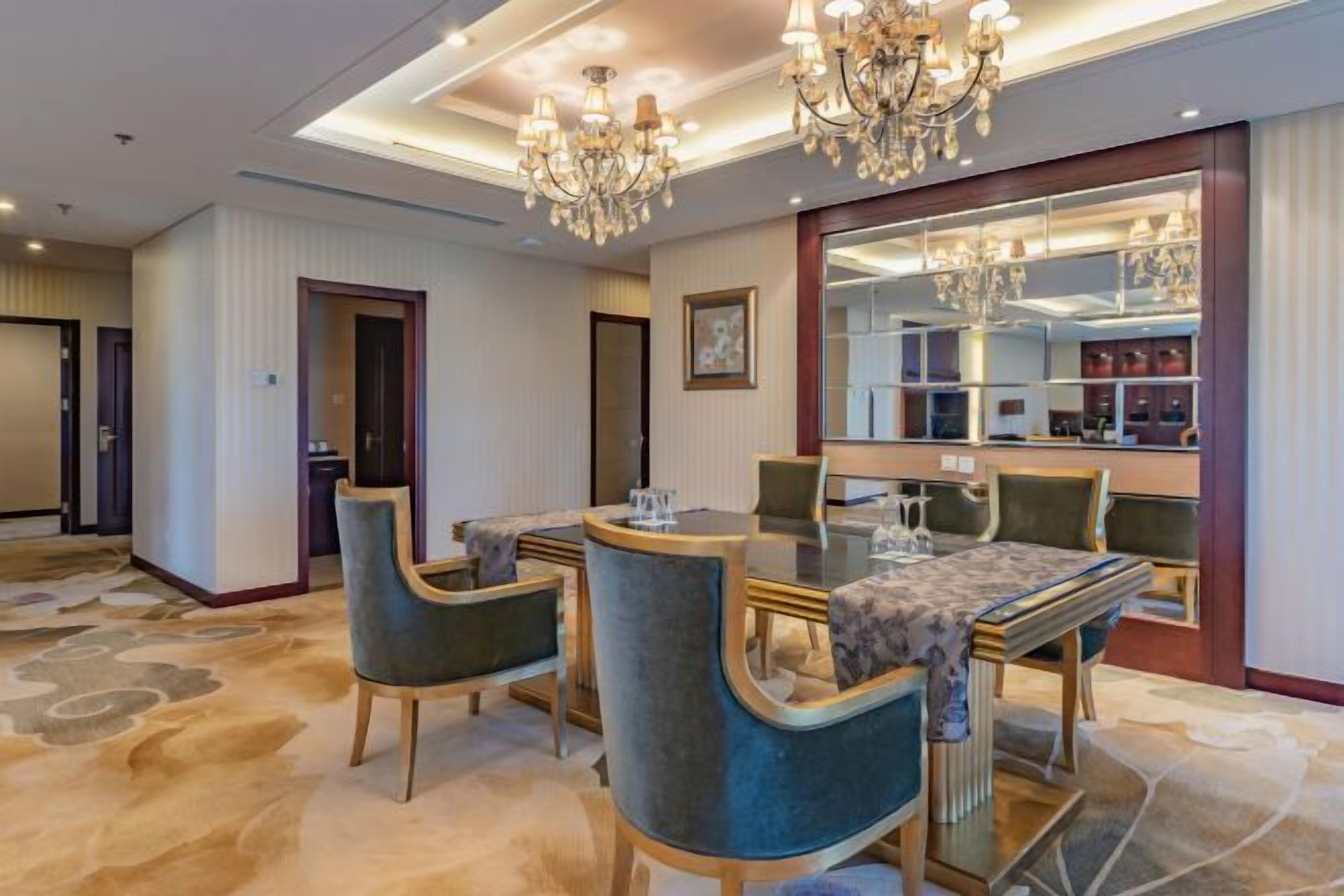 Un comedor de hotel con una gran mesa redonda, sillas tapizadas y un candelabro.