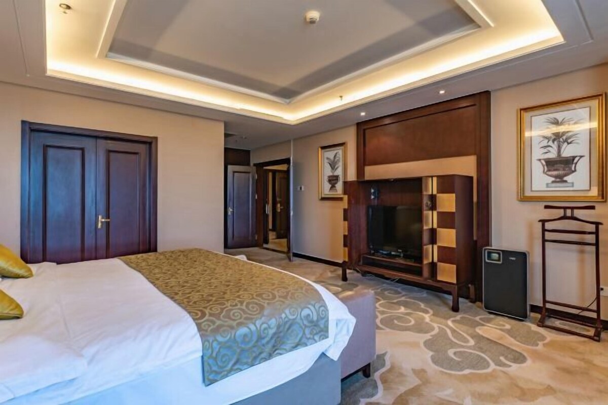 Quarto de hotel com uma cama grande, lareira, televisão e uma mesinha.