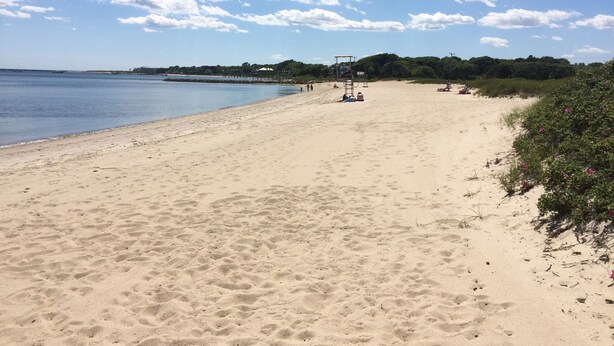 A wide sandy beach with a lifeguard tower and a calm sea. - Steps to the beach with an ocean view,  (Barnstable)