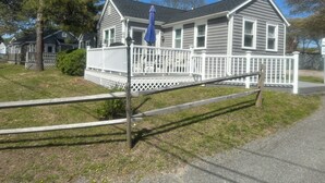A two-story house with a white porch and a blue umbrella. - Steps to the beach with an ocean view,  (Barnstable)