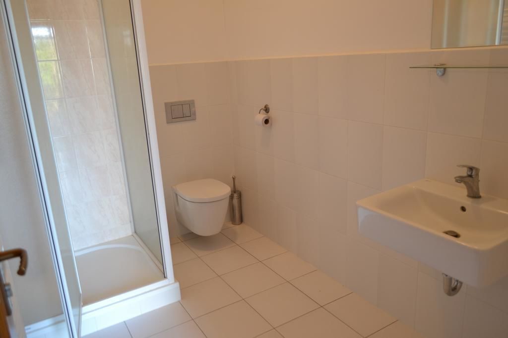 A bathroom with a toilet, sink, and shower area.