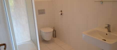Un baño con inodoro, lavabo y cabina de ducha.