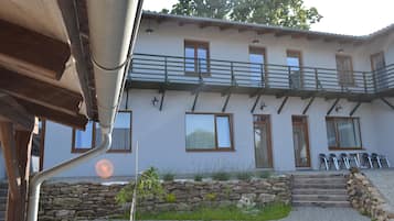 A two-story building with a stone wall and steps leading to the entrance.