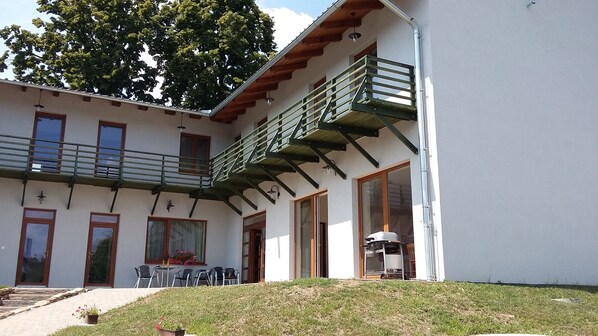 A two-story building with a balcony, outdoor seating, and a small garden area. - Farm Kundratice (Kundratice)