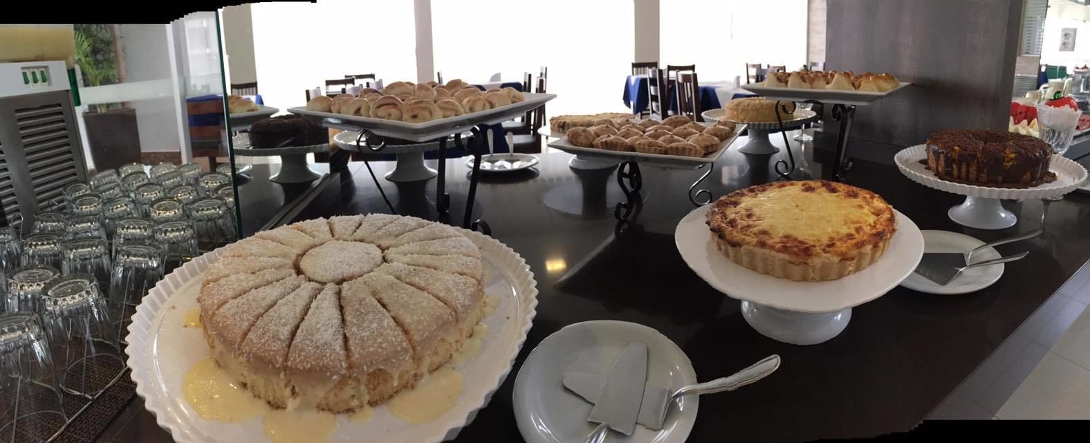 Una mesa de buffet con diversos postres, incluyendo un pastel grande con diseño de abanico, una tarta y varios productos horneados más pequeños.