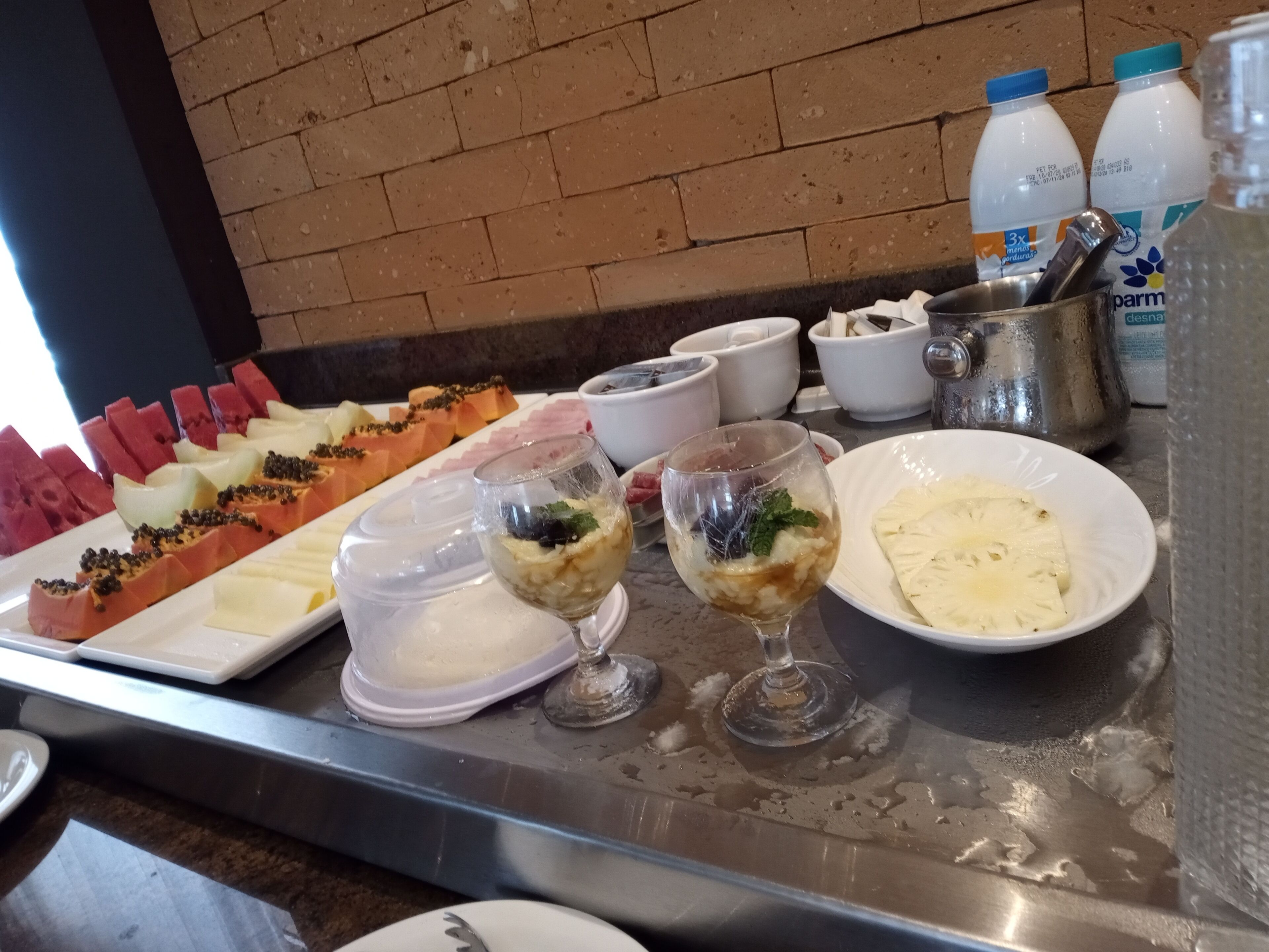A buffet table with various dishes, including fruits, desserts, and beverages.