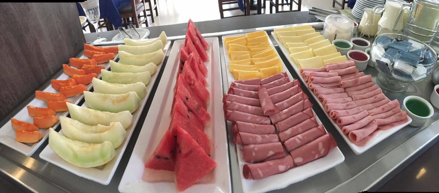 Buffet com diversos alimentos, incluindo fatias de melão, queijo e carne.