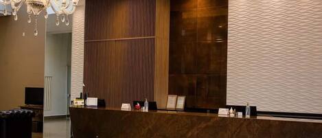 A reception desk with a modern design, a chandelier, and a textured wall.