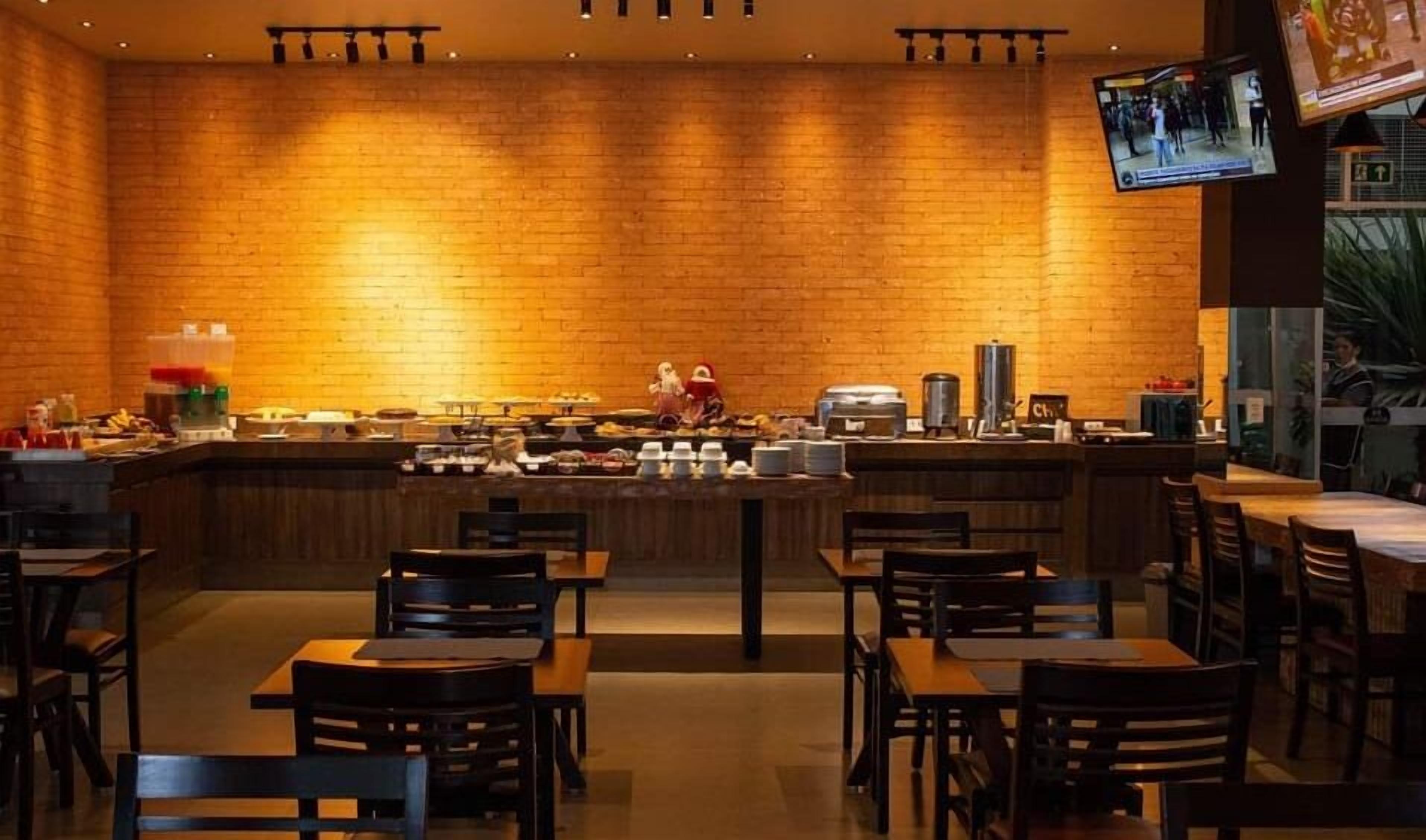 Ein Restaurant mit Backsteinwänden, einer Bar und mehreren Tischen und Stühlen.