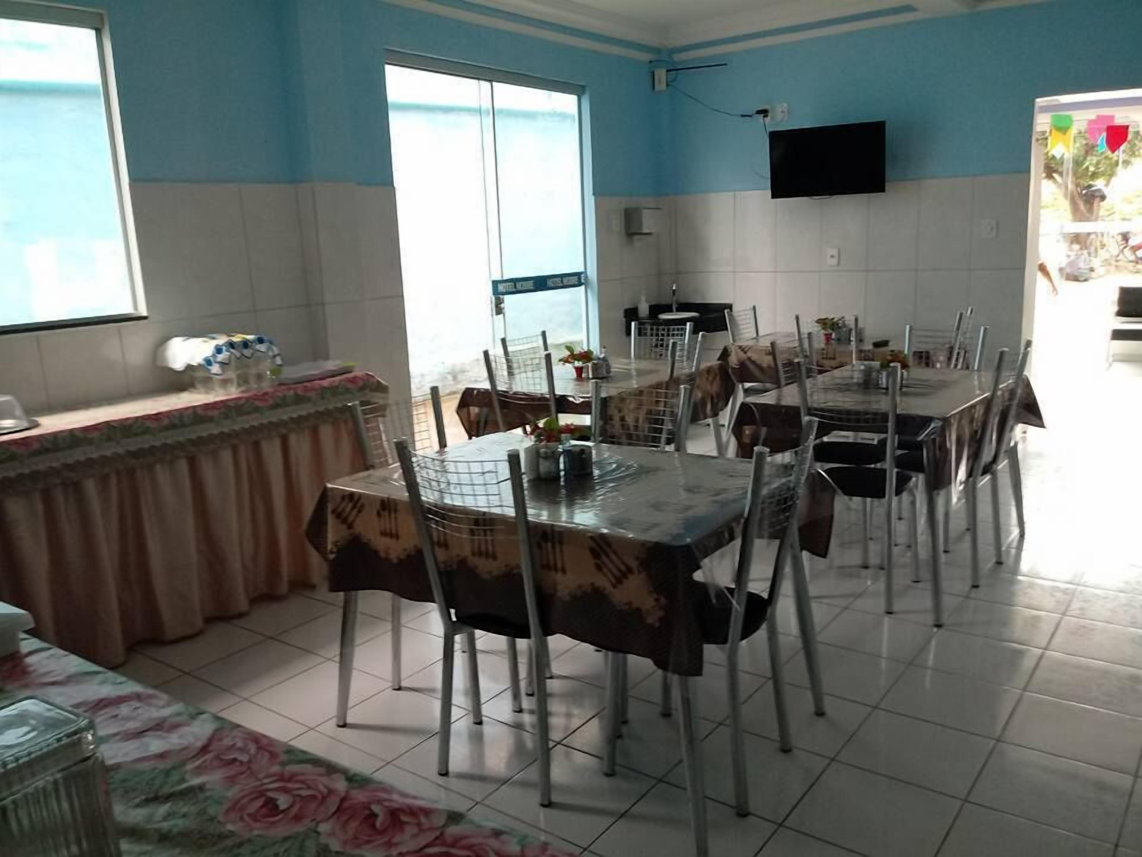 A dining area with a large table and chairs, a counter with a sink, and a television mounted on the wall.