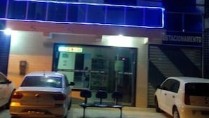 A hotel with a sign reading "Hotel Nobre" and a visible entrance. There are cars parked in front, and a bench is placed outside the entrance.