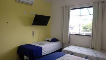 Una habitación con dos camas, aire acondicionado, televisión y ventana con cortinas.