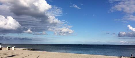 Ein Strand mit klarem Himmel, ruhiger See und sandigem Ufer.