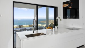 Une cuisine moderne dotée d’une grande fenêtre donnant sur une vue imprenable sur la côte.