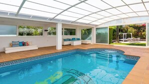 An indoor swimming pool with a geometric tile pattern, white walls, and a glass ceiling. - Ohana1 Luxury villa. (Málaga)