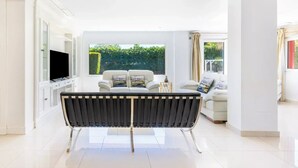 A modern living room with a black and white bench, a white sofa, and a TV on a cabinet. - Ohana1 Luxury villa. (Málaga)