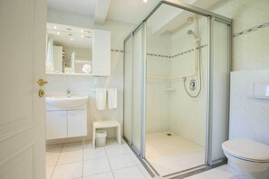 Een moderne badkamer met een douchecabine van glas, een wastafel en een toilet.