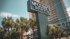 A sign for McGure's Irish Pub with a modern building in the background.