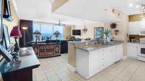 A spacious kitchen with a large island, white cabinets, and a view of the ocean.