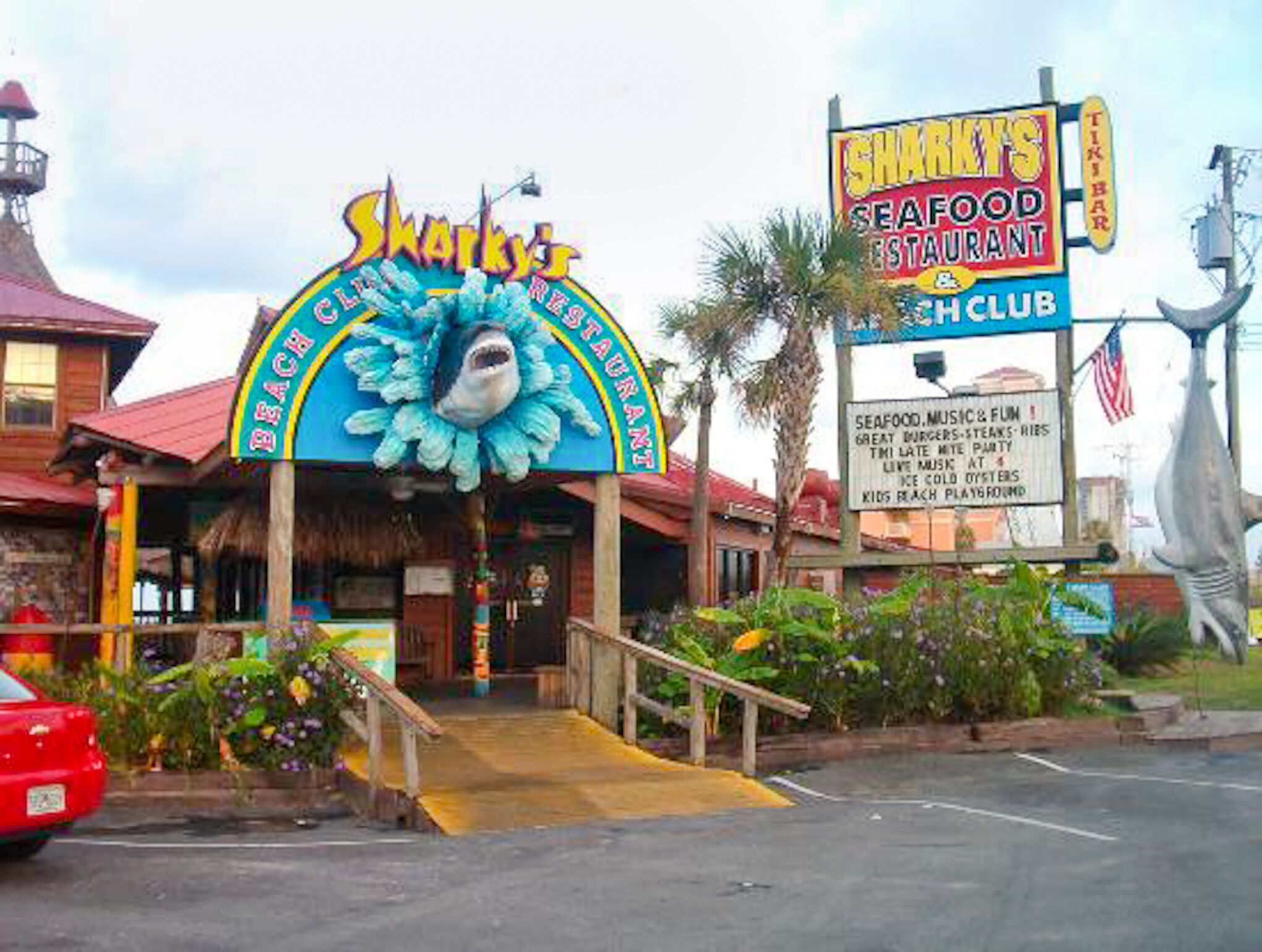 A beachfront restaurant named Sharky's Seafood Restaurant with a shark mascot sign.