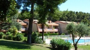 A hotel with multiple balconies, a swimming pool, and lush greenery. - T2 by the sea, 150 m to the beach/sea, TOPP prices, FREE: WLAN, pool, tennis (Le Pradet)
