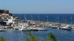 A marina with boats docked, a rocky shoreline, and buildings in the background. - T2 by the sea, 150 m to the beach/sea, TOPP prices, FREE: WLAN, pool, tennis (Le Pradet)