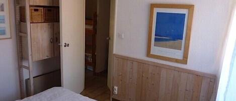 A bedroom with a bed, wooden wardrobe, and a framed picture on the wall.