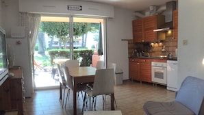 A compact living space with a dining area, a kitchenette, and a view of the outdoors. - T2 by the sea, 150 m to the beach/sea, TOPP prices, FREE: WLAN, pool, tennis (Le Pradet)