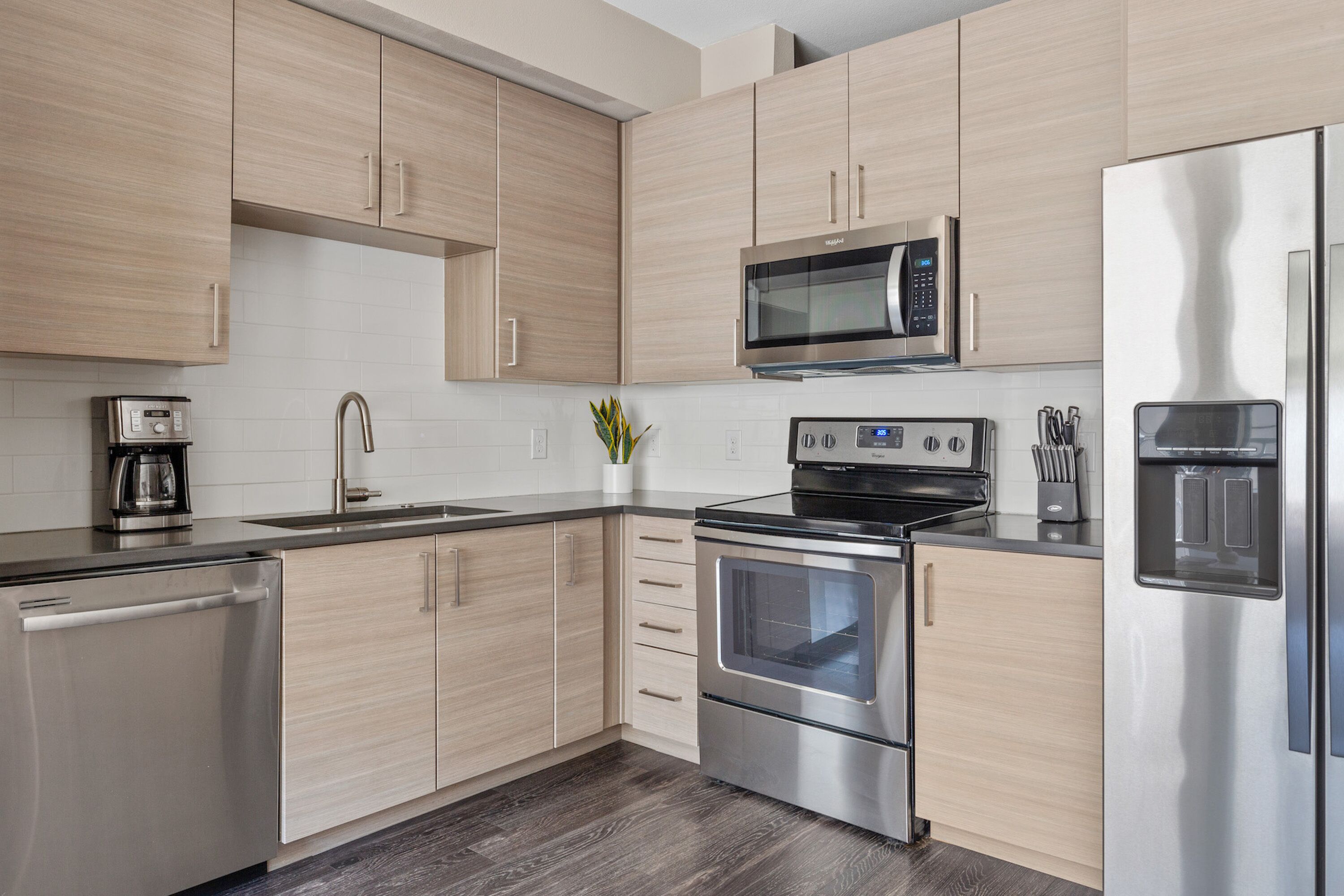 Een moderne keuken met roestvrijstalen apparatuur, licht houten kastjes en een inbouwoven.