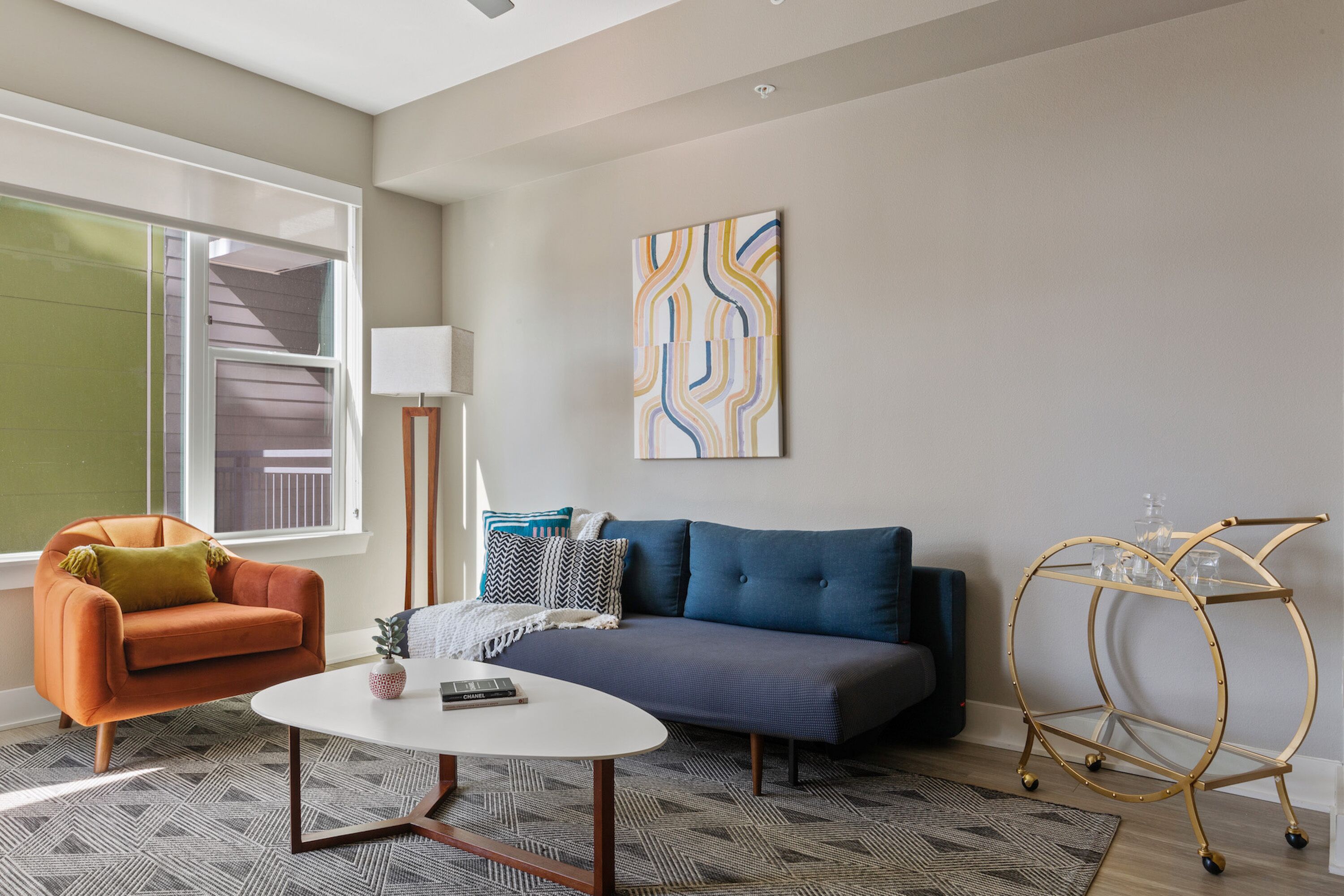 A modern living room with a sofa, armchair, coffee table, and a decorative cart.