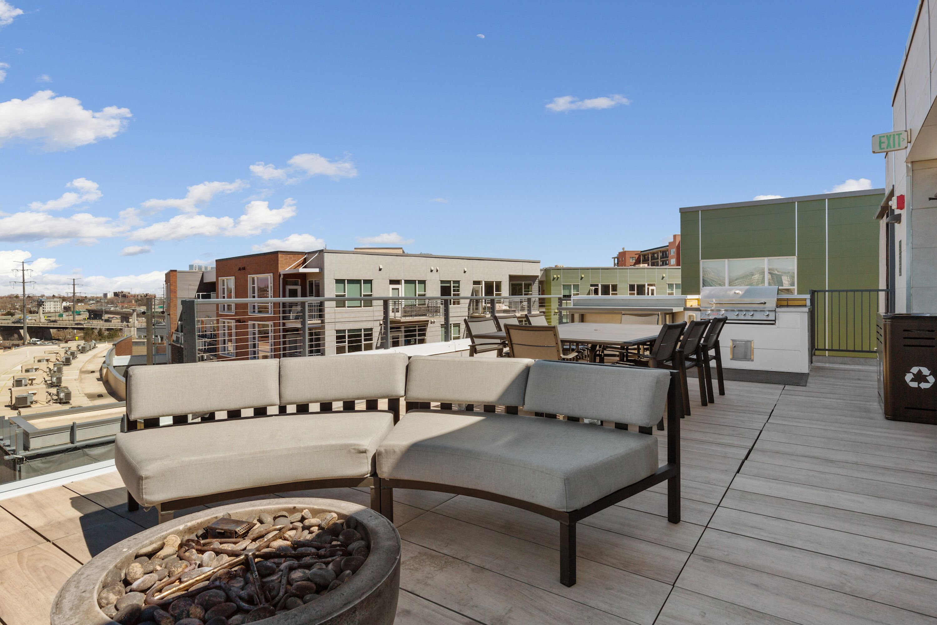 Una terraza en la azotea con un brasero, mobiliario exterior y vistas de la ciudad.
