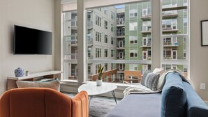 A modern living room with a large window, a flat-screen TV, a sofa, and a coffee table. - Kasa Union Station Denver (Denver)