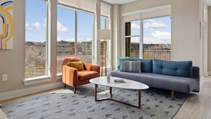 A spacious living room with large windows, a modern sofa, a coffee table, and an orange armchair. - Kasa Union Station Denver (Denver)