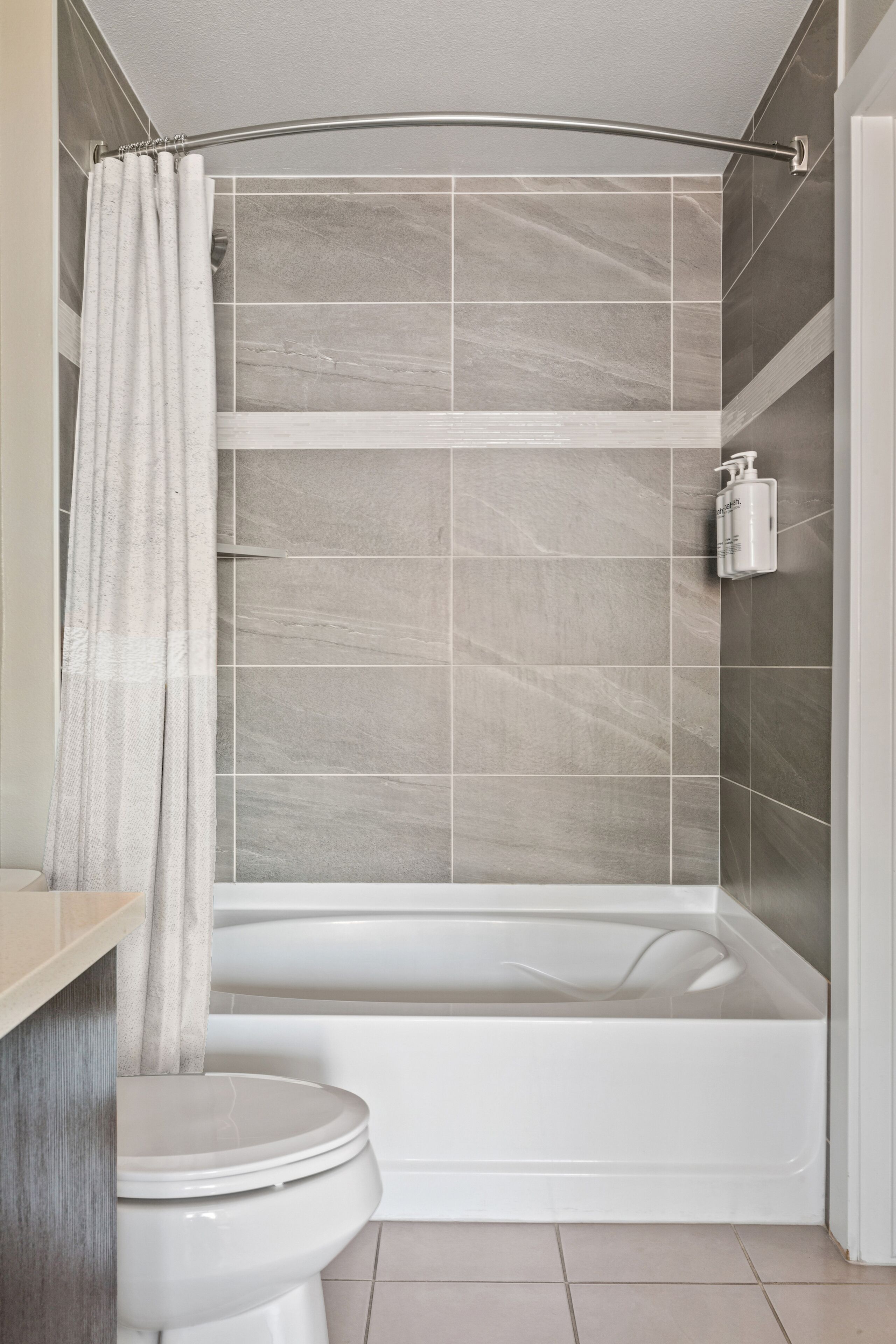 A bathroom with a bathtub, toilet, and shower curtain.