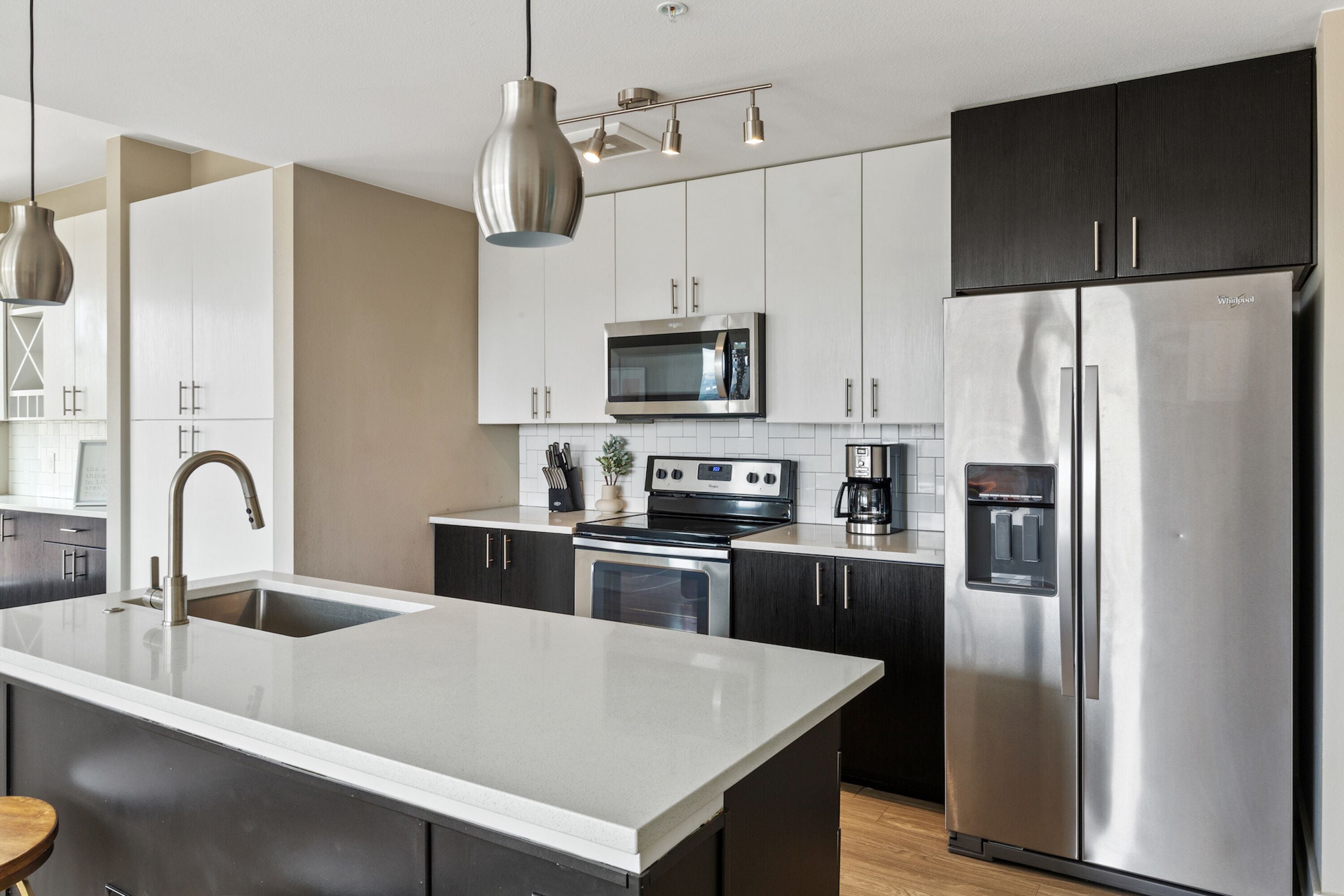 A modern kitchen with stainless steel appliances, a central island, and dark cabinetry.