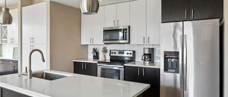 A modern kitchen with stainless steel appliances, a central island, and dark cabinetry.