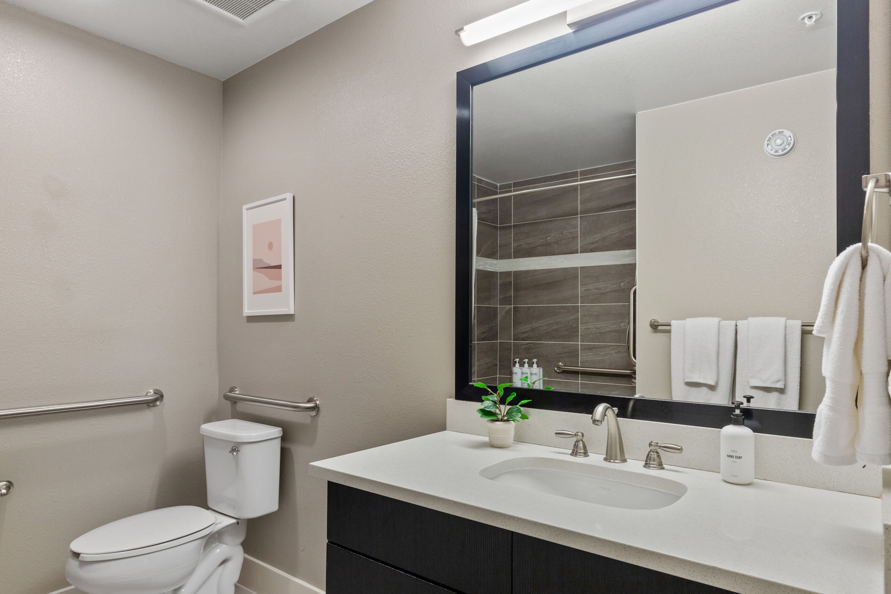 Un baño moderno con un lavabo blanco, un espejo grande y un inodoro.
