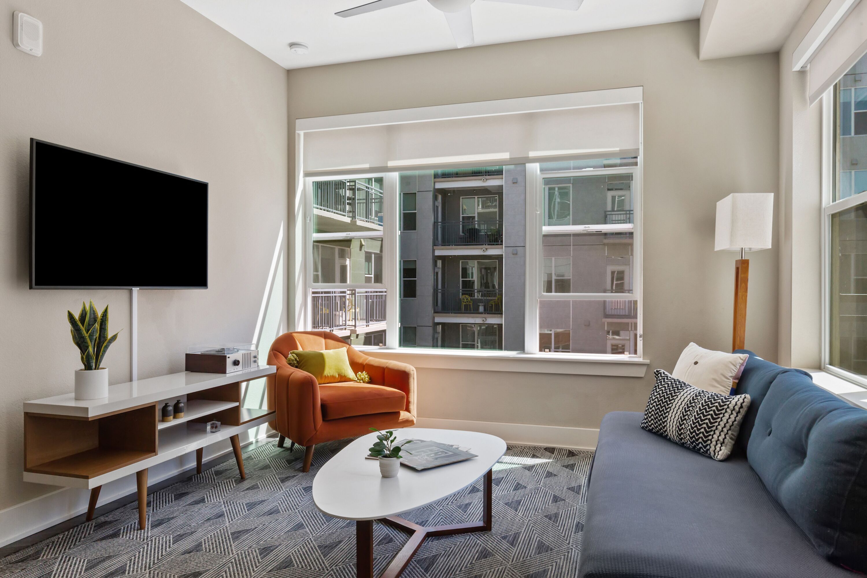 A modern living room with a flat-screen TV, a sofa, a coffee table, and a chair.