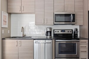 Una cocina moderna con electrodomésticos de acero inoxidable, incluyendo microondas, cafetera, lavavajillas y horno.