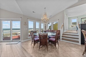 A spacious dining area with a glass table and wicker chairs, overlooking a balcony with a view of the ocean. - 4099 - 3-2-1 Relax - Duck Oceanfront Retreat | Sleeps 22, Pool, Hot Tub (Duck)