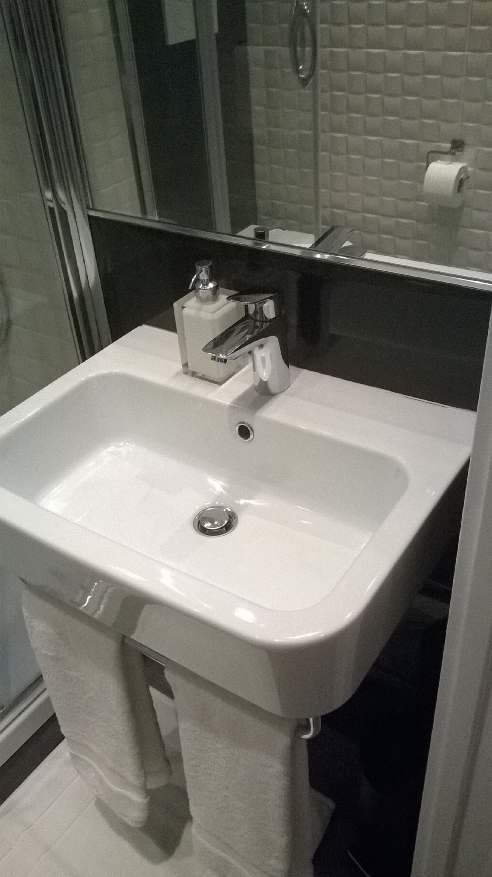 A bathroom with a white sink, a mirror, and a towel rack.