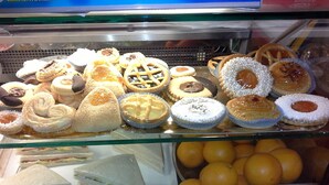 Una vitrina con varios pasteles y sándwiches.