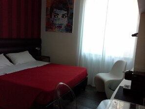 A hotel room with a bed, a chair, a table, and a painting on the wall. - Il Cavaliere B&B (Rome)