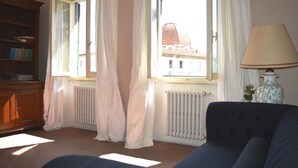 A room with a blue sofa, a wooden bookshelf, and a window with white curtains.