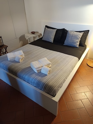 A modern bedroom with a large bed, two pillows, and neatly folded towels.