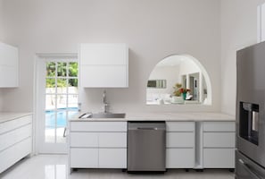 A modern kitchen with white cabinetry, a stainless steel dishwasher, and a large island with a sink. - Beautiful Open Plan Villa On 3,000  of Living Space at No 1 Queens Fort (St James)
