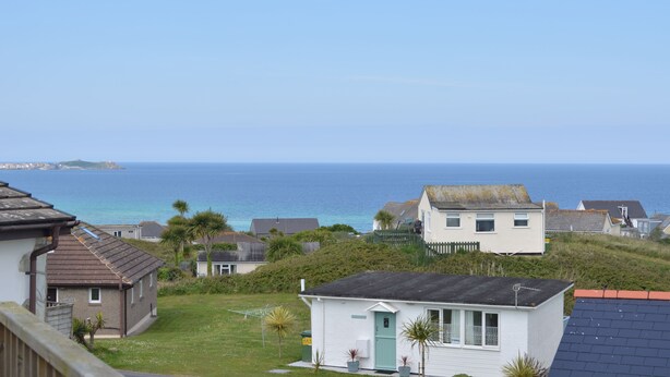 Zona residencial costera con casas, un césped y vista al mar.
