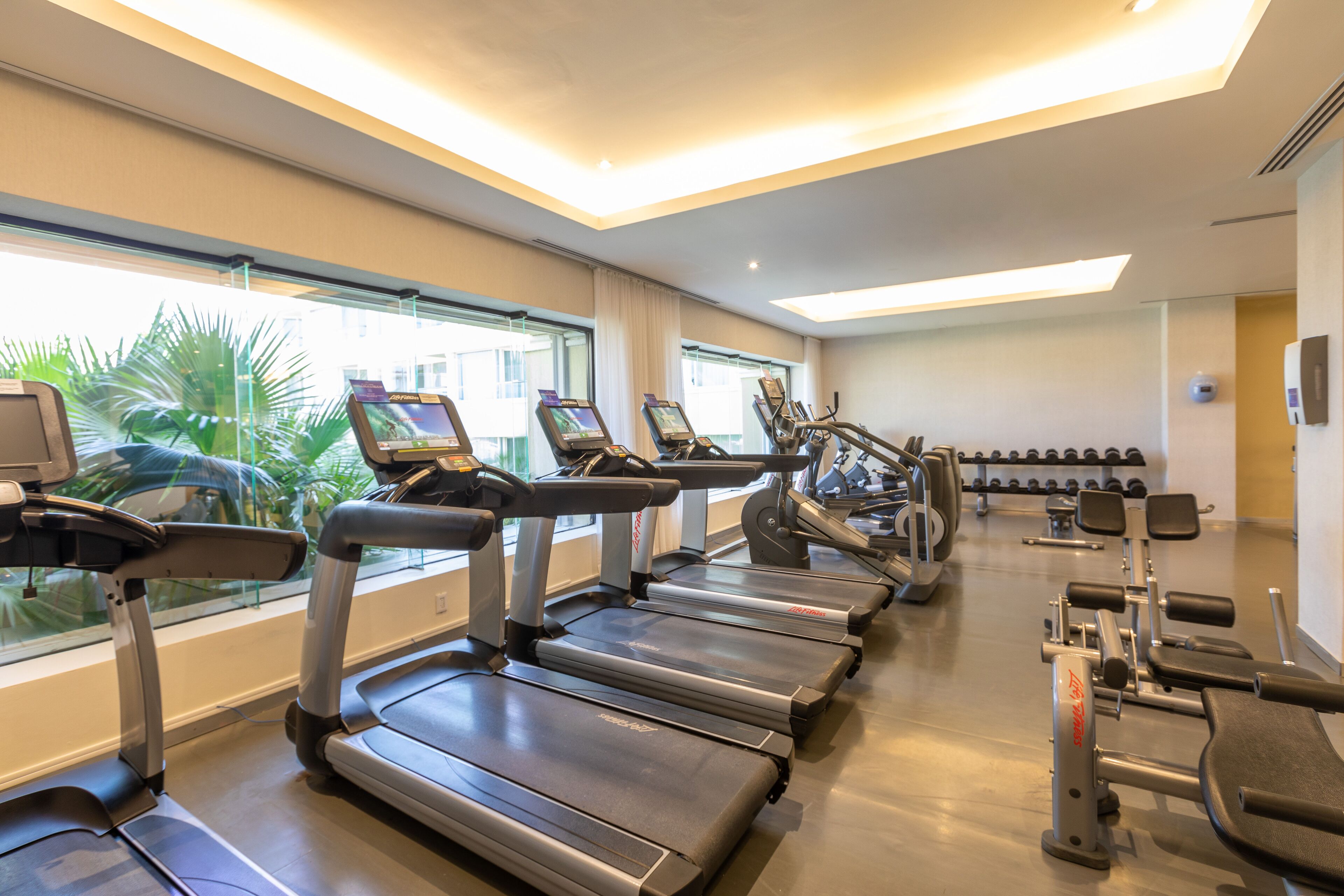 A gym with treadmills, weight machines, and dumbbells.